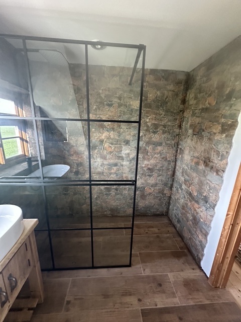 Crittall walk-in shower against exposed stone wall