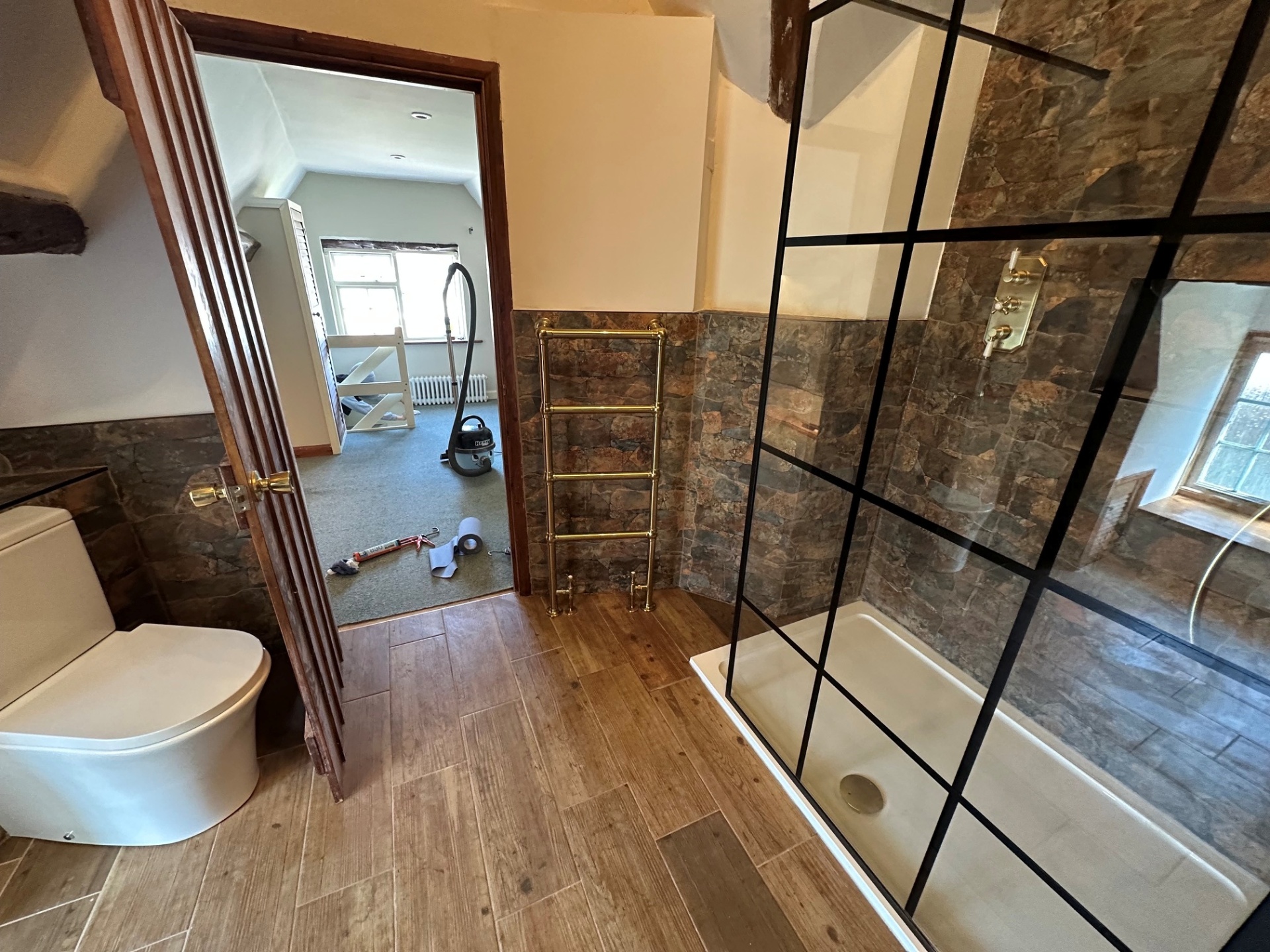 Beamed bathroom with brass towel rail & crittall screen