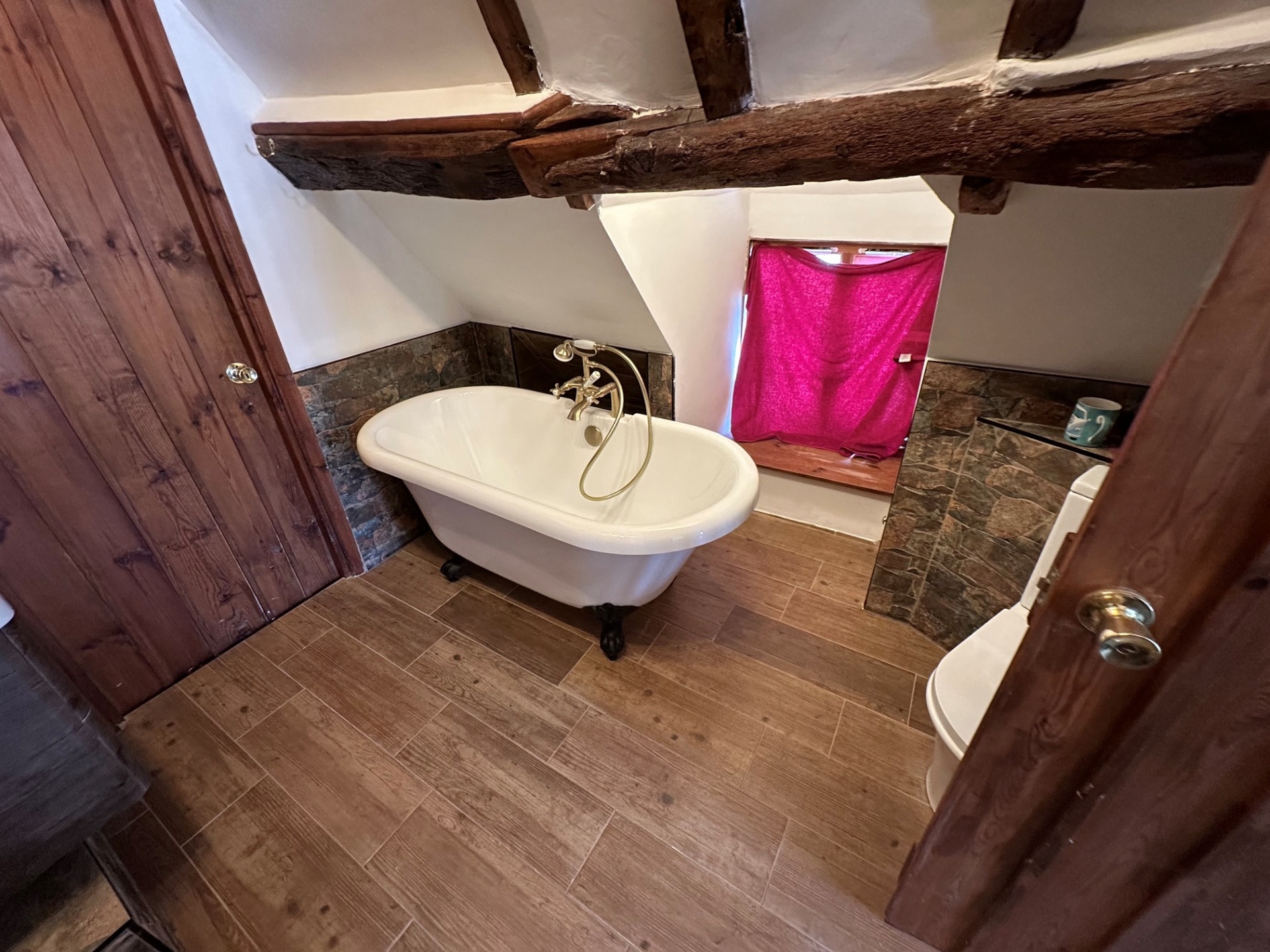 Roll-top clawfoot bath in a beamed cottage bathroom